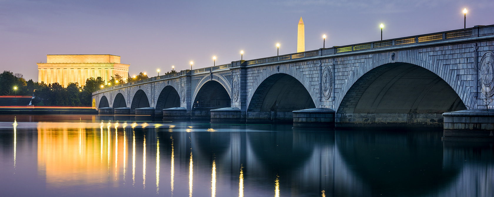 Arlington Bridge lit up at night with DC Skyline featuring Lincoln Memorial and Washington Monument 