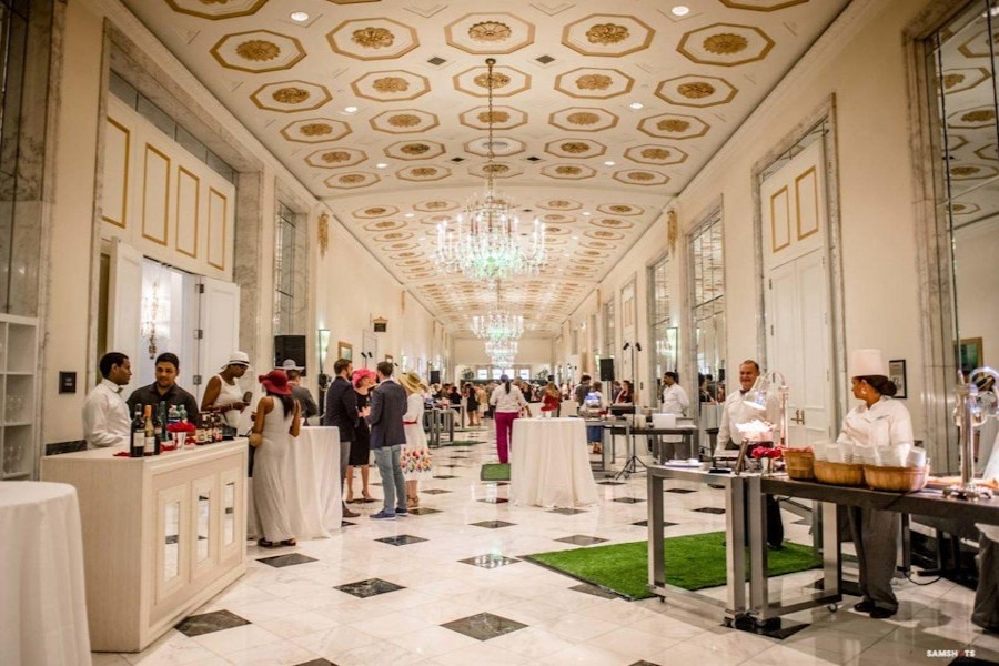 Guests mingle and enjoy food and drinks in an elegant marble hall at The Mayflower Hotel in Washington, DC.