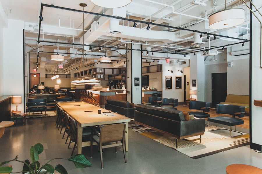 Eaton DC’s first-floor communal lounge and workspace with long wooden tables, modern seating, and warm pendant lighting.