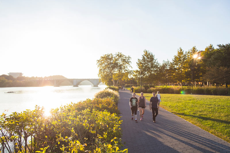 People walking along Georgetown Waterfront Park on a sunny afternoon in Washington, DC