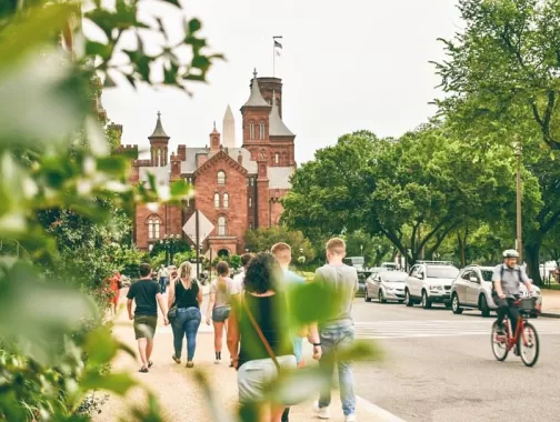 Visitors walking by the Smithsonian Castle on the National Mall in Washington, DC