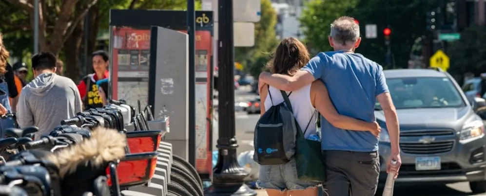 A couple walks arm in arm past a row of Capital Bikeshare bikes in the Adams Morgan neighborhood of Washington, DC.