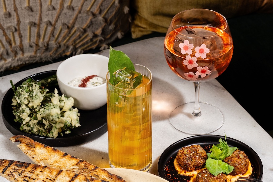 A professional photo of a table filled with colorful food, including a cherry blossom cocktail. 