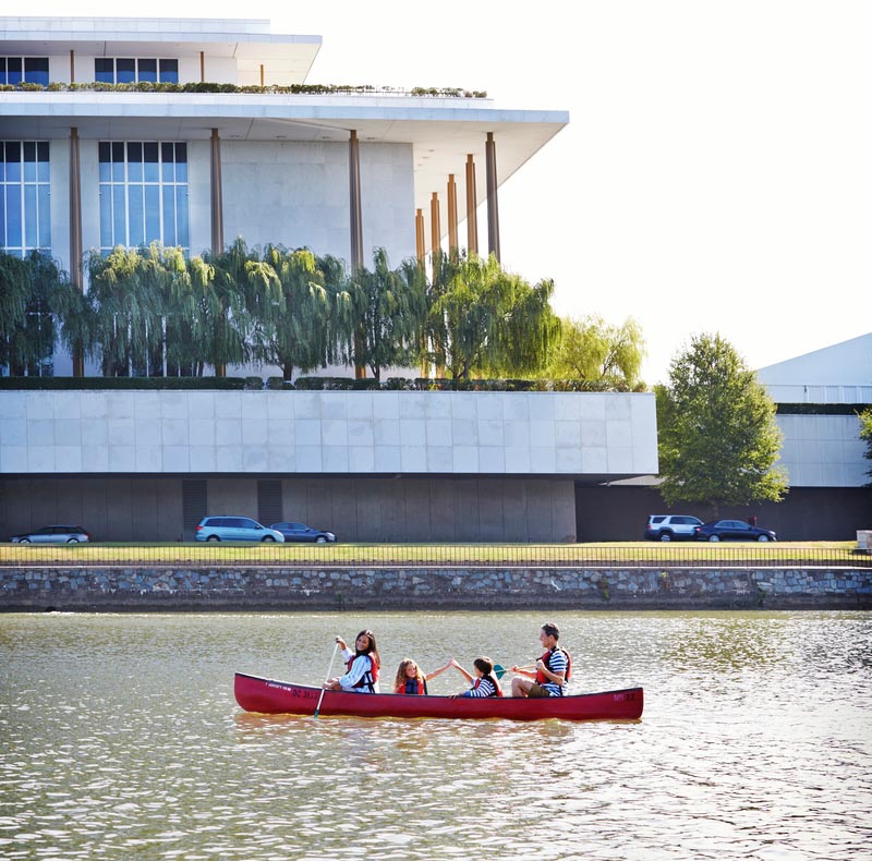 Family canoeing on Potomac River past Kennedy Center, Washington DC