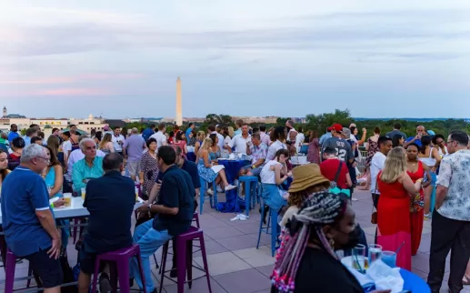 attendees gather on a rooftop overlooking the Washington Monument
